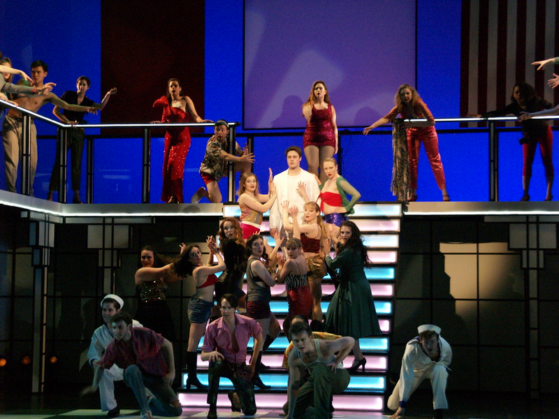 a group of actors and actresses dancing on stage