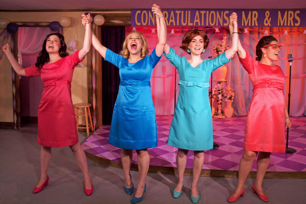 four actresses in dresses holding their hands up